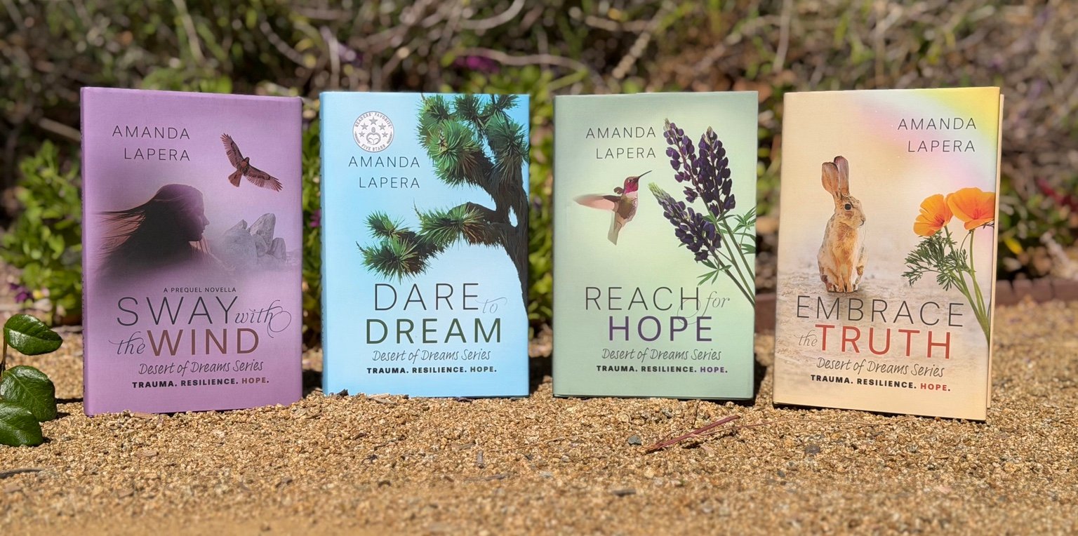 Four Desert of Dreams books standing together outdoors in the desert.